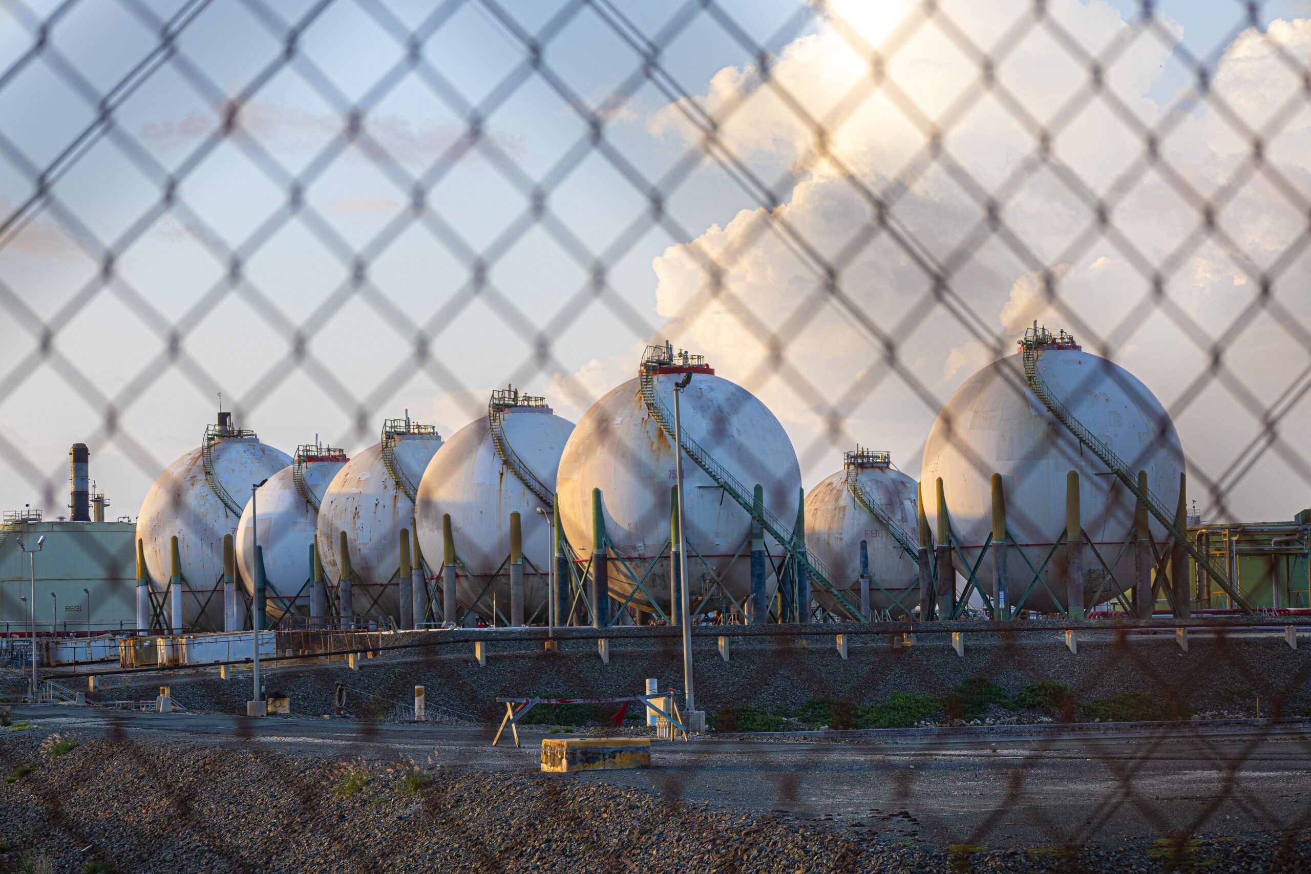 Several large industrial oil tanks stand side by side in a factory setting